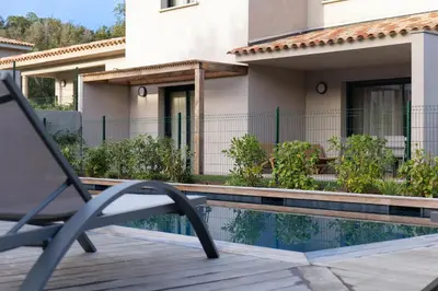 a chair sitting on a deck next to a swimming pool at résidence Terra Verde in Porto-Vecchio