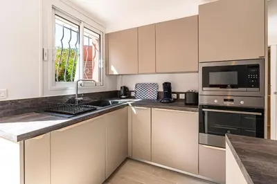 a kitchen with white cabinets and a sink and a microwave at Canelli - Magnifique Vue Mer in Pietrosella