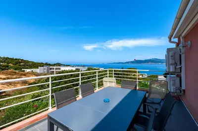 a balcony with a blue table and chairs and the ocean at Canelli - Magnifique Vue Mer in Pietrosella