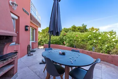 a blue table with chairs and an umbrella on a patio at Canelli - Magnifique Vue Mer in Pietrosella