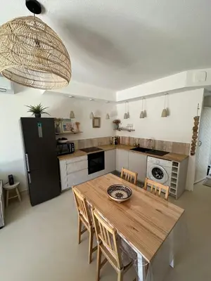 a kitchen with a wooden table with chairs and a refrigerator at La Villa des Sables Borgu in Borgo