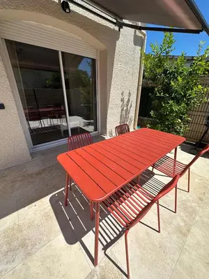 a red picnic table and two chairs on a patio at La Villa des Sables Borgu in Borgo