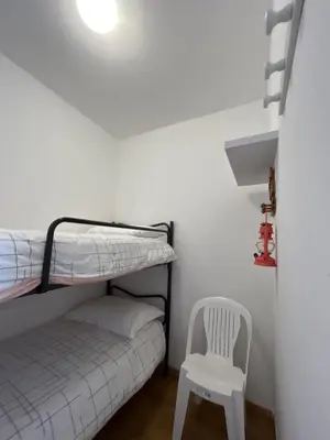 a bedroom with a bunk bed and a white chair at Hôtel Punta e Mare des Chambres ou des Appartements T2 in Cargèse