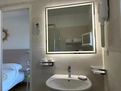 a bathroom with a sink and a mirror at Hôtel Punta e Mare des Chambres ou des Appartements T2 in Cargèse