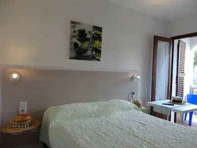 a bedroom with a bed and a picture on the wall at Hôtel Punta e Mare des Chambres ou des Appartements T2 in Cargèse