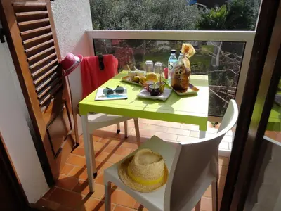 a small green table and chair on a balcony at Hôtel Punta e Mare des Chambres ou des Appartements T2 in Cargèse