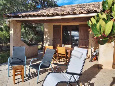 a patio with chairs and a table and a house at Villa Surleau in Zonza