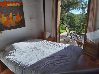 a bedroom with a bed and a door to a patio at Villa Surleau in Zonza
