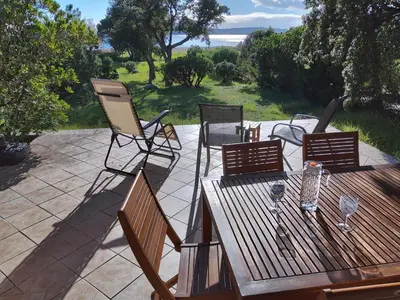 a patio with a wooden table and four chairs at Villa Surleau in Zonza