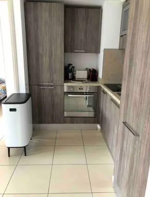 a small kitchen with wooden cabinets and a trash can at propriano pieds dans l eau in Propriano