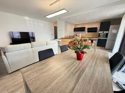 a living room with a table with a vase of flowers on it at Confortable T3 10 min plage in Lucciana