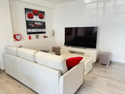 a living room with a white couch and a television at Confortable T3 10 min plage in Lucciana