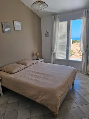 a bedroom with a large bed and a large window at Les Terrasses du Levant in Porto-Vecchio
