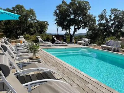 a swimming pool with lounge chairs and an umbrella at Domaine LOADANA in Sainte-Lucie de Porto-Vecchio