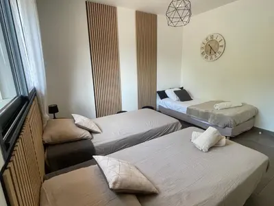 a room with three beds and a clock on the wall at Domaine LOADANA in Sainte-Lucie de Porto-Vecchio