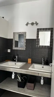 a bathroom with two sinks and two mirrors at Domaine LOADANA in Sainte-Lucie de Porto-Vecchio