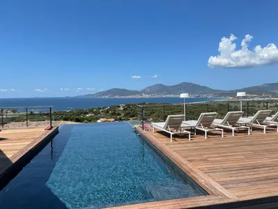 a pool with lounge chairs on a wooden deck at Villa Clémentines Porticcio in Grosseto-Prugna