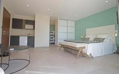 a bedroom with a bed and a table and a kitchen at Villa Clémentines Porticcio in Grosseto-Prugna