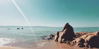 a beach with rocks and water and the ocean at Glamping luxe entre mer et maquis in Ajaccio