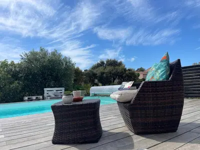 two chairs sitting on a deck next to a swimming pool at Villa Amacali vue mer piscine chauffée climatisée in Sainte-Lucie de Porto-Vecchio