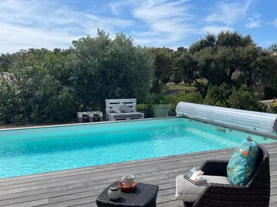 a swimming pool with two chairs and a table next to it at Villa Amacali vue mer piscine chauffée climatisée in Sainte-Lucie de Porto-Vecchio
