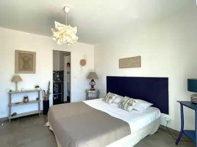 a bedroom with a large bed and a chandelier at Villa Amacali vue mer piscine chauffée climatisée in Sainte-Lucie de Porto-Vecchio