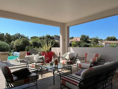 a patio with chairs and tables and a pool at Villa Amacali vue mer piscine chauffée climatisée in Sainte-Lucie de Porto-Vecchio