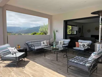 a living room with couches and a large window at Villa Amacali vue mer piscine chauffée climatisée in Sainte-Lucie de Porto-Vecchio