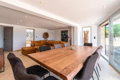 a dining room with a wooden table and chairs at Le Roc - RDC - Splendide Vue Mer in Coti-Chiavari