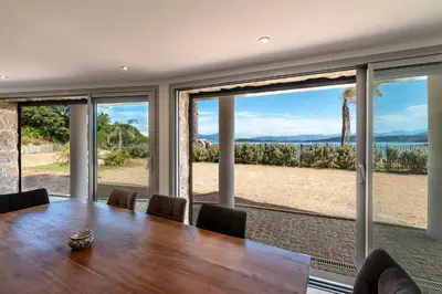 a dining room with a table and large sliding glass doors at Le Roc - RDC - Splendide Vue Mer in Coti-Chiavari