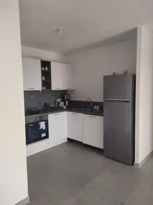 a kitchen with white cabinets and a stainless steel refrigerator at Appartement Carpe diem vue mer plage à pied in Conca