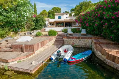 two boats are docked in the water in front of a house at Villa Sempietru, 8 pers, lagon & plage à pied in Lecci