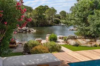 a garden with a river and a wooden deck at Villa Sempietru, 8 pers, lagon & plage à pied in Lecci