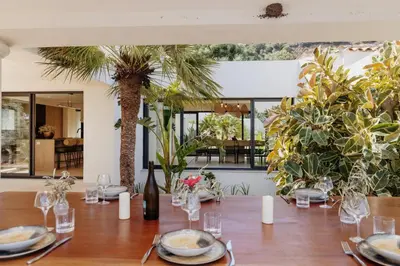 a table with plates and a bottle of wine and palm trees at Balamb Garden A Rinascita in Ajaccio