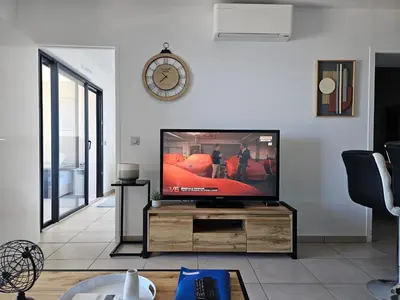 a living room with a television and a clock on the wall at 1vue,1 lieu, Des vacances in Pietrosella