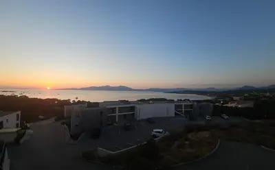 a sunset over a building with a parking lot at 1vue,1 lieu, Des vacances in Pietrosella