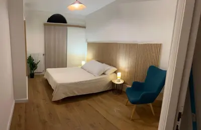 a bedroom with a bed and a blue chair at Le nid des agrumes in Lucciana