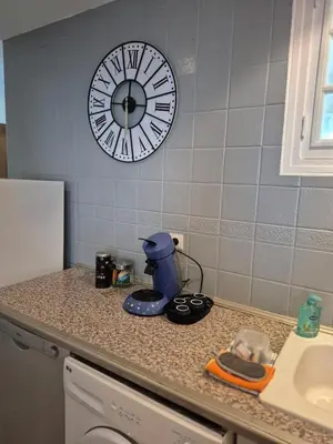 a kitchen counter with a coffee maker and a clock on the wall at Le nid des agrumes in Lucciana