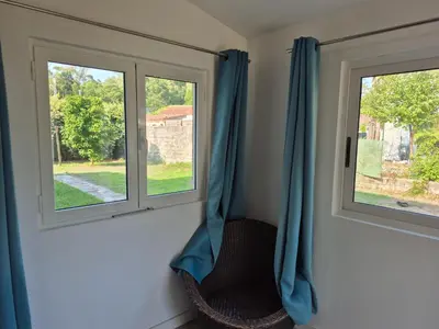 two windows with blue curtains in a room at Le nid des agrumes in Lucciana