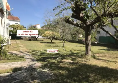 a sign in a yard with a tree and a house at Le nid des agrumes in Lucciana
