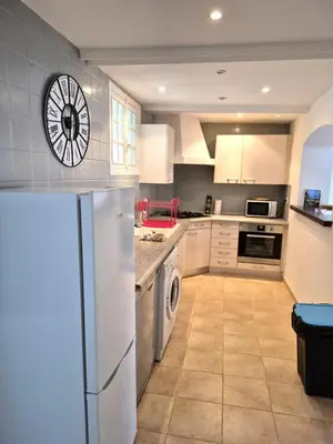 a kitchen with a refrigerator and a clock on the wall at Le nid des agrumes in Lucciana