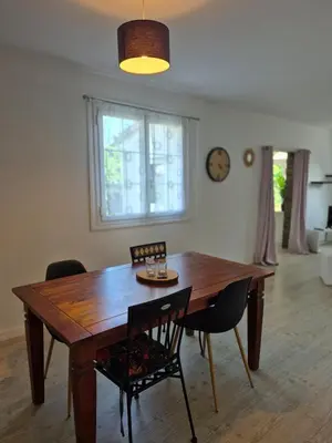 a dining room table with chairs and a clock on the wall at Le nid des agrumes in Lucciana