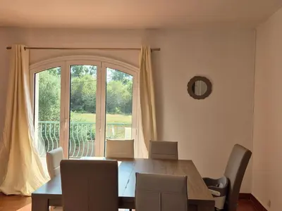 a dining room table with chairs and a large window at Chez nous in Lucciana