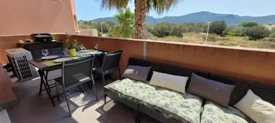 a balcony with a couch and a table and a grill at T2 Port de Porto Vecchio 4 pers vue Montagne in Porto-Vecchio