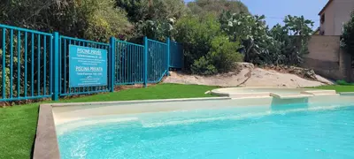 a swimming pool next to a blue fence at T2 Port de Porto Vecchio 4 pers vue Montagne in Porto-Vecchio