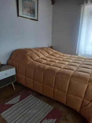 a bed in a bedroom with a large brown blanket at Appartement Casa Rose in Sollacaro
