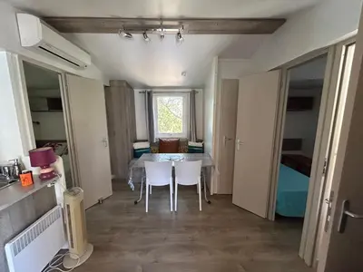 a dining room with a table and white chairs at Mobil-Home U Forconu in Pianottoli-Caldarello