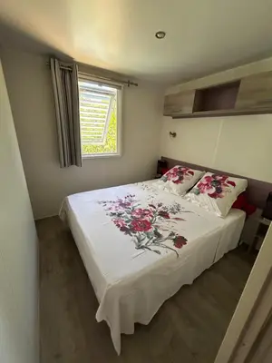a bedroom with a bed with red flowers on it at Mobil-Home U Forconu in Pianottoli-Caldarello