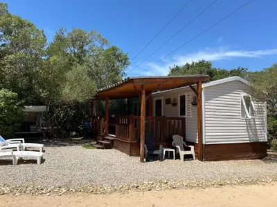 a cabin with a deck and chairs in front of it at Mobil-Home U Forconu in Pianottoli-Caldarello