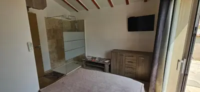 a bedroom with a bed and a shower and a television at Bed and kitchen with pool in Aléria